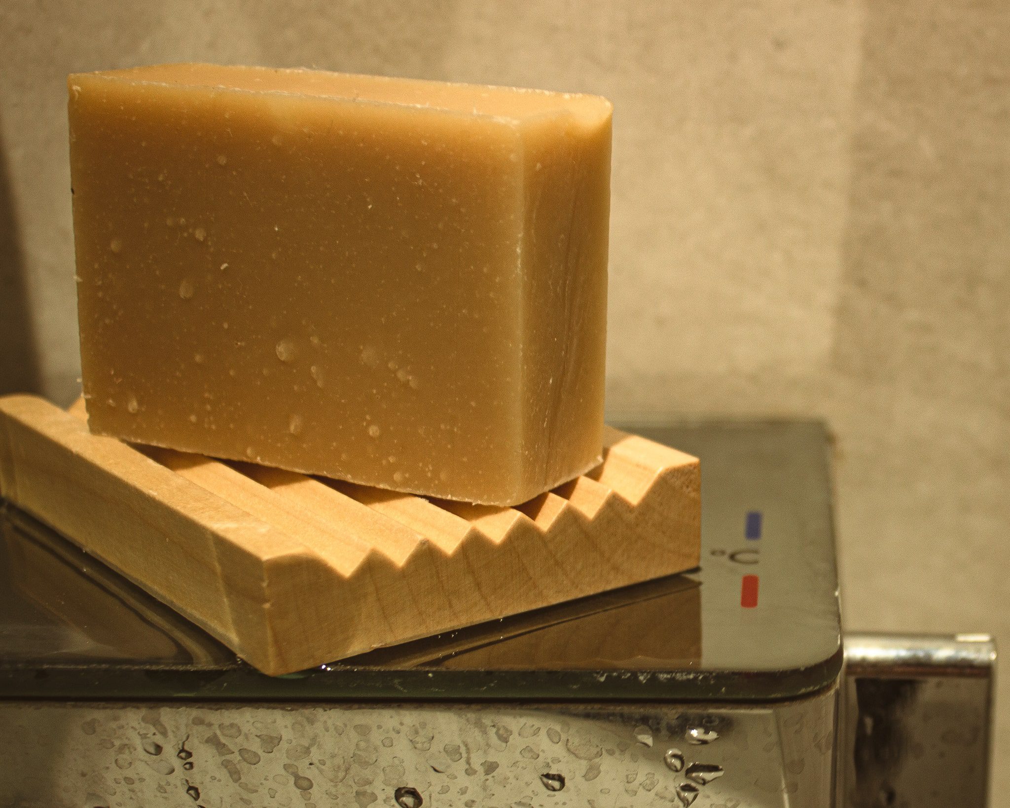 Goat Milk Soap in shower, the bar of soap is resting on a wood soap tray.